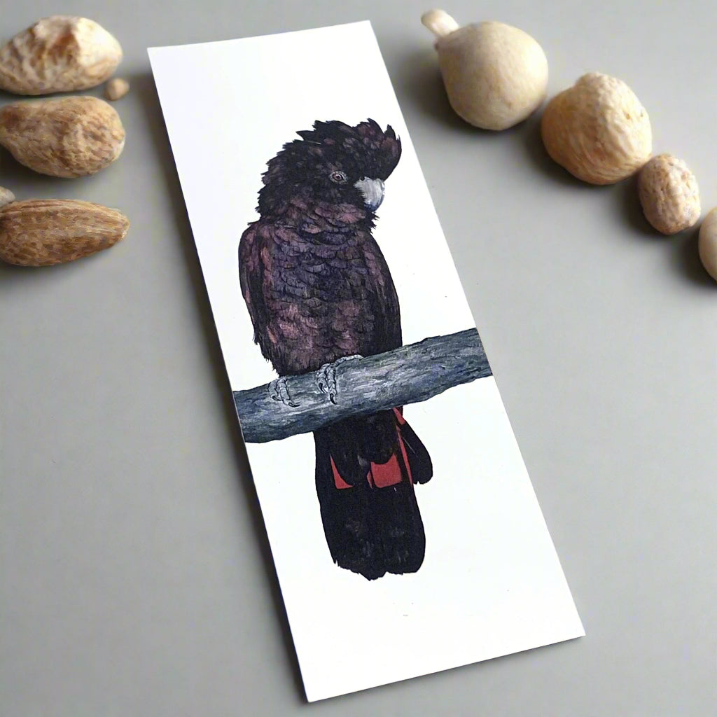 A bookmark featuring a watercolor painting of a red-tailed black cockatoo perched on a branch with a white background.