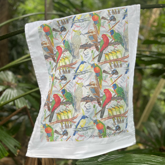 Colorful bird-patterned towel hanging against a green leafy background