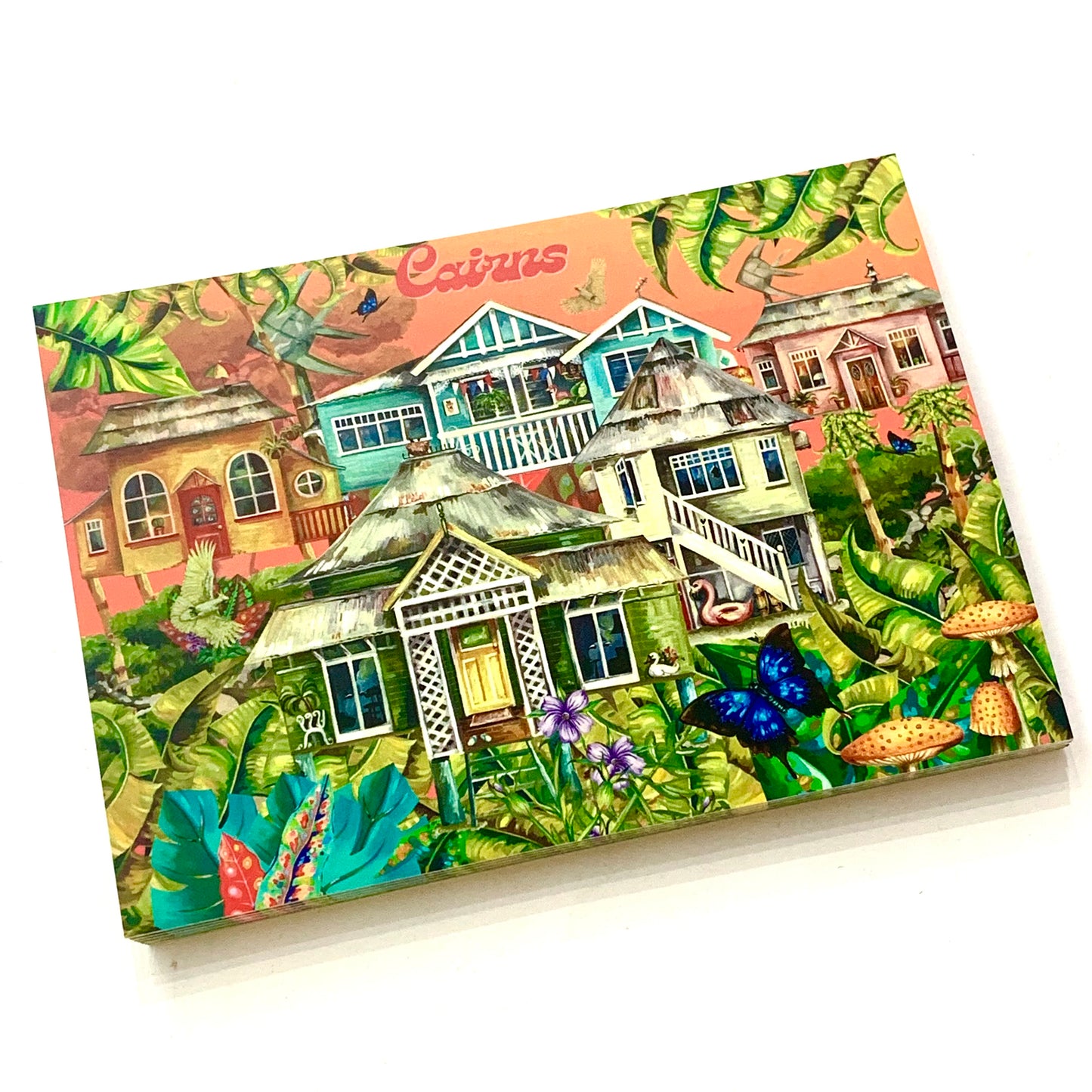 A postcard featuring an artistic depiction of Queenslanders style houses in Cairns with a colorful and tropical backdrop.