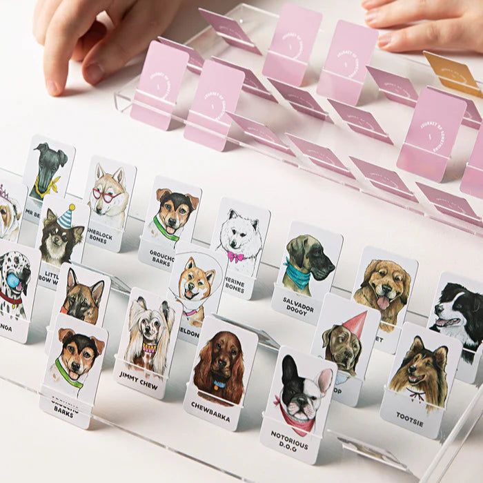 Card game with dog-themed cards and pink card holders on a white surface.