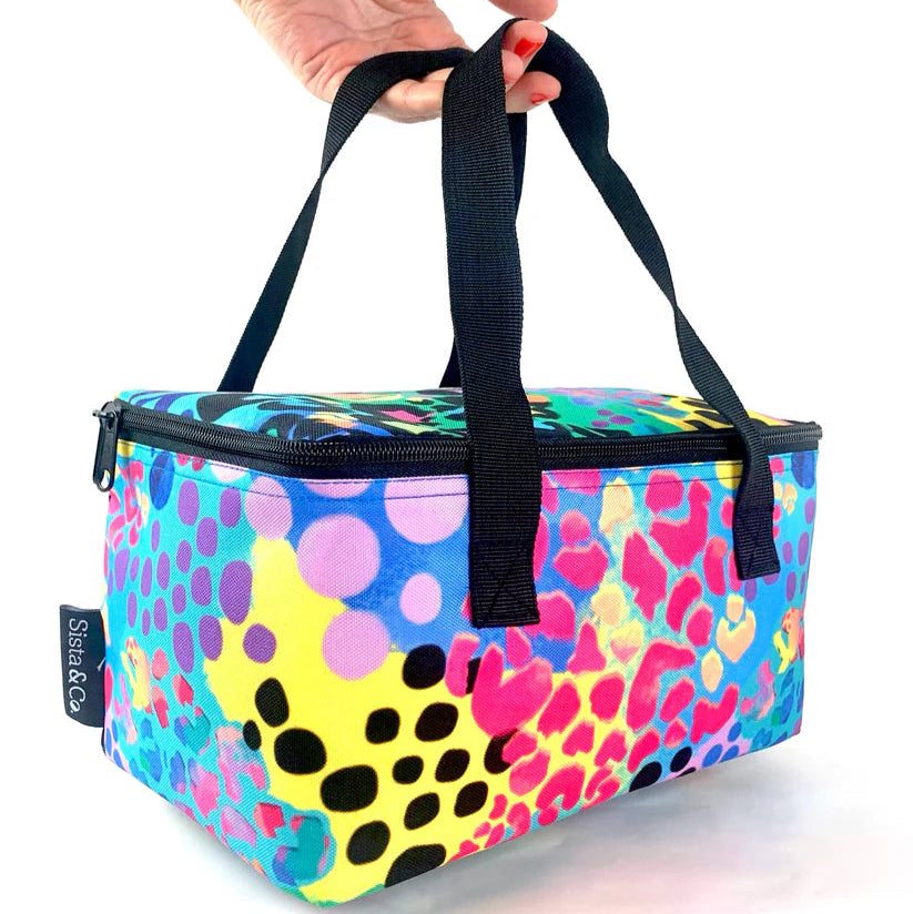 Colorful leopard print cooler bag with black handles held by a hand on a white background