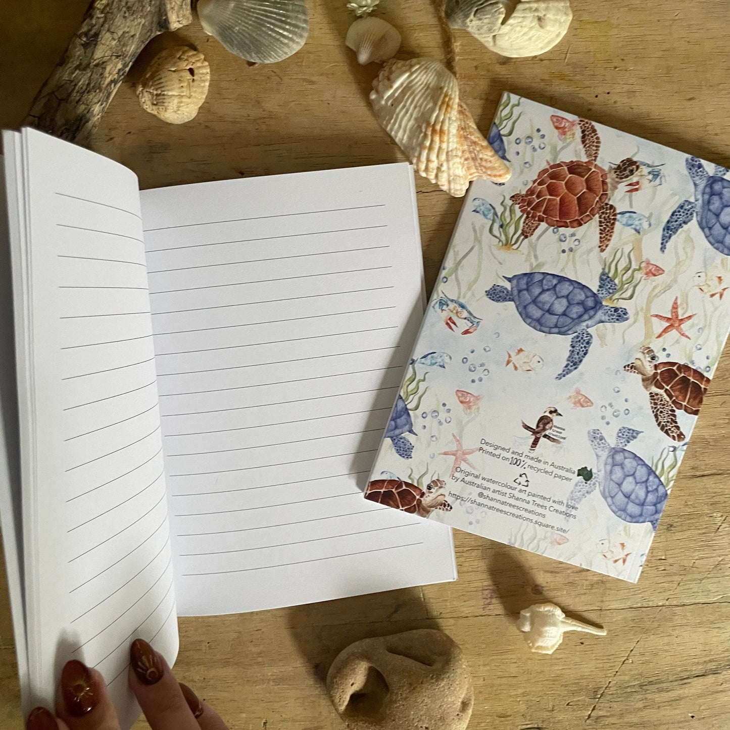 Open notebook on a wooden surface with sea-themed stationery items