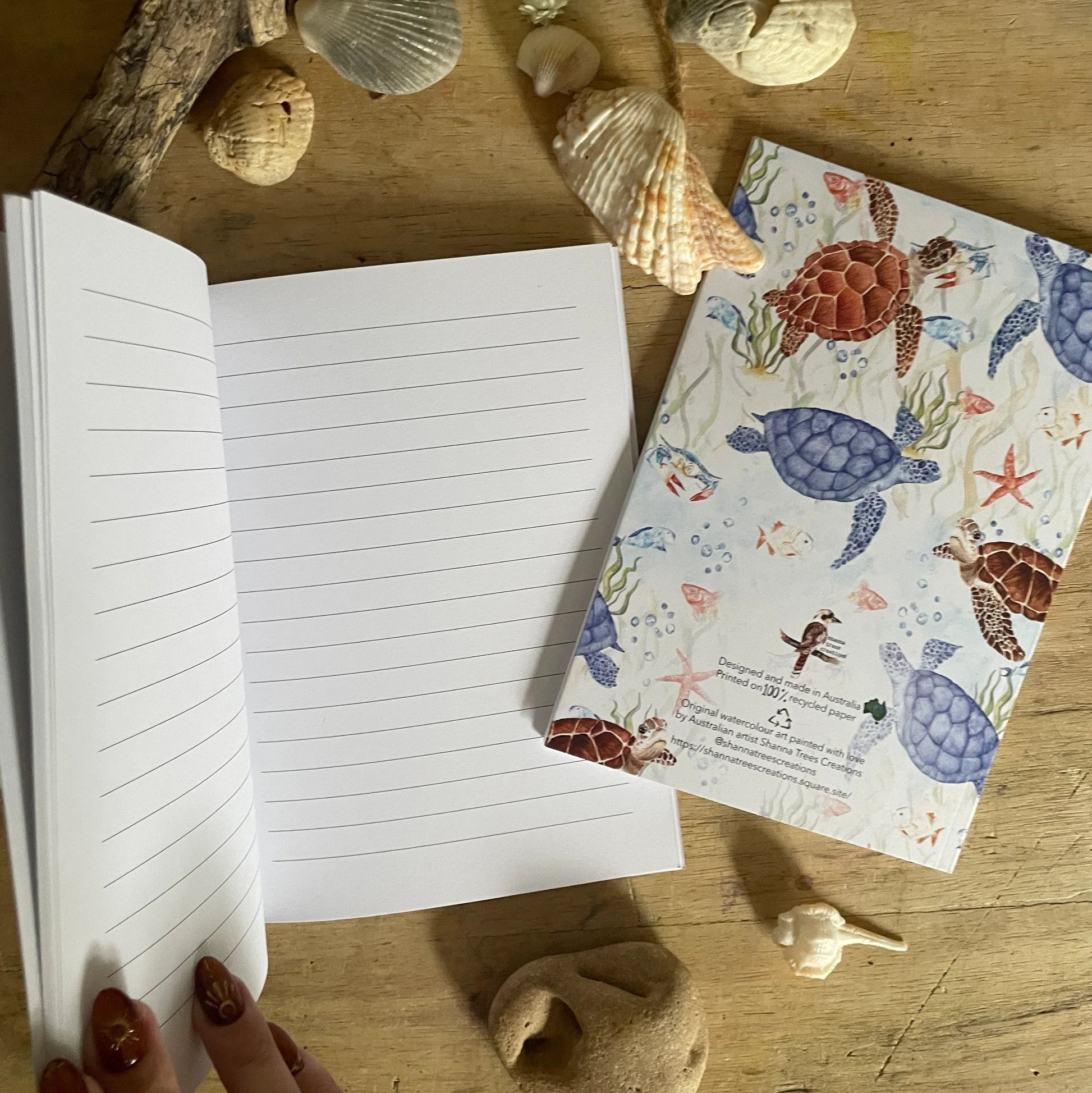 Open notebook on a wooden surface with sea-themed stationery items