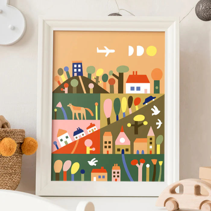 Framed colorful children's wall art on a white wall with toys around.